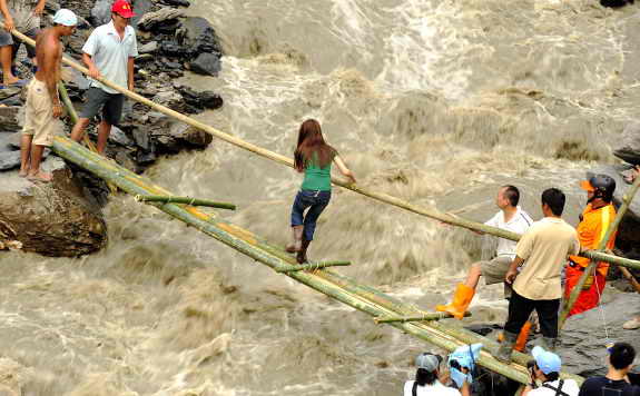 Девушка старается перейти бушующий поток воды через импровизированный мостик во время наводнения в деревне Хсинфа, на юге Тайваня
