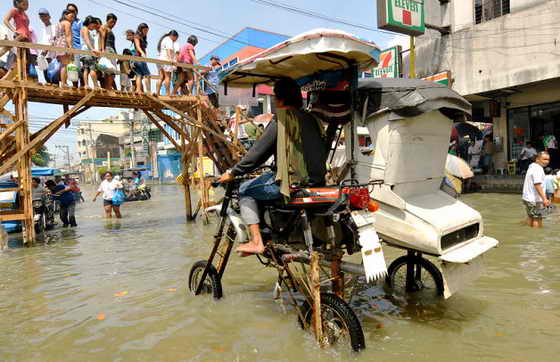 В столице Филиппин Маниле до сих пор не прекращаются обильные дожди после того, как по острову прошел тропический ураган Кетсана. На фото местный житель пытается проехать на мотоцикле по затопленной улице 