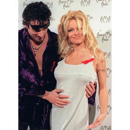 Томми Ли гладит живот беременной жены, Памелы Андерсон, во время 23-й Ежегодной Церемонии American Music Awards в 1996. Они поженились в 1995 году, спустя 96 часов после встречи