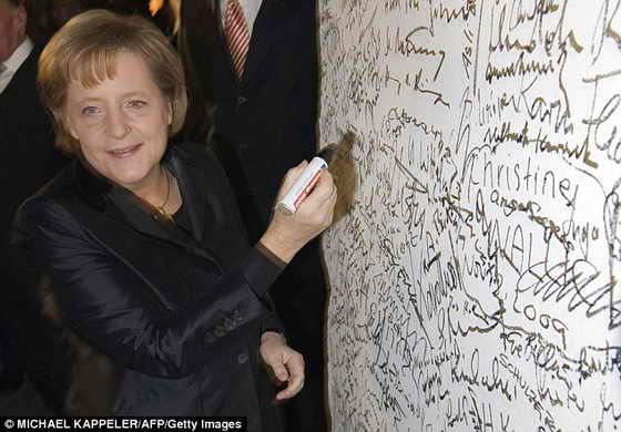 Канцлер Германии Ангела Меркель ставит свою подпись на Берлинской стене, открывая праздник в честь падения стены в 1989 году