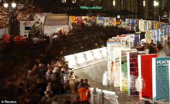 Толпы людей проходят возле домино, символизирующих Берлинскую стену