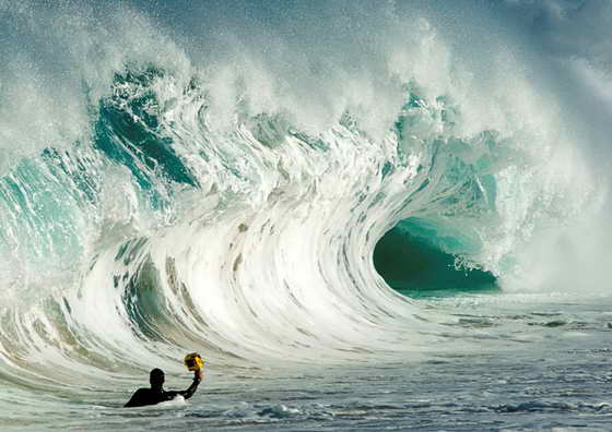 Кларк Литтл делает фотографии волны, находясь в воде, недалеко от гавайского пляжа Laniakea