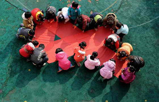 Дети пишут свои имена на красной ленточке во время акции по поднятию осведомленностьи о ВИЧ / СПИДе в детском саду в Хэфэй, провинция Аньхой, Китай