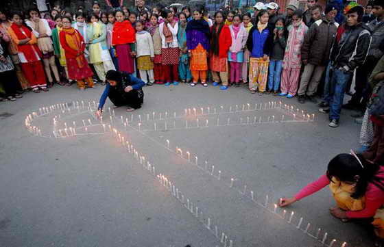 Люди молятся, стоя со свечами, в одном из центров для ВИЧ-инфицированных детей и женщин, ставшими жертвами торговли людьми в Катманду, Непал