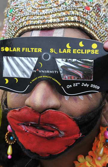 Индийский художник Б. Nookaджи, одетый как индусский бог-обезьяна Ханумана, использует специальные солнечные очки, чтобы посмотреть на солнечное затмение в Хайдарабаде