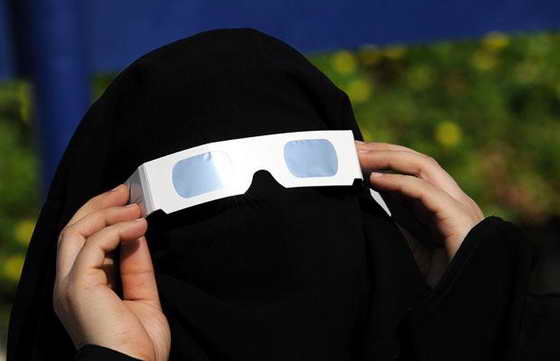 Женщина из Саудовской Аравии использует специальные очки с тонированными стеклами для наблюдения за частичным солнечным затмением в портовом городе Джидда